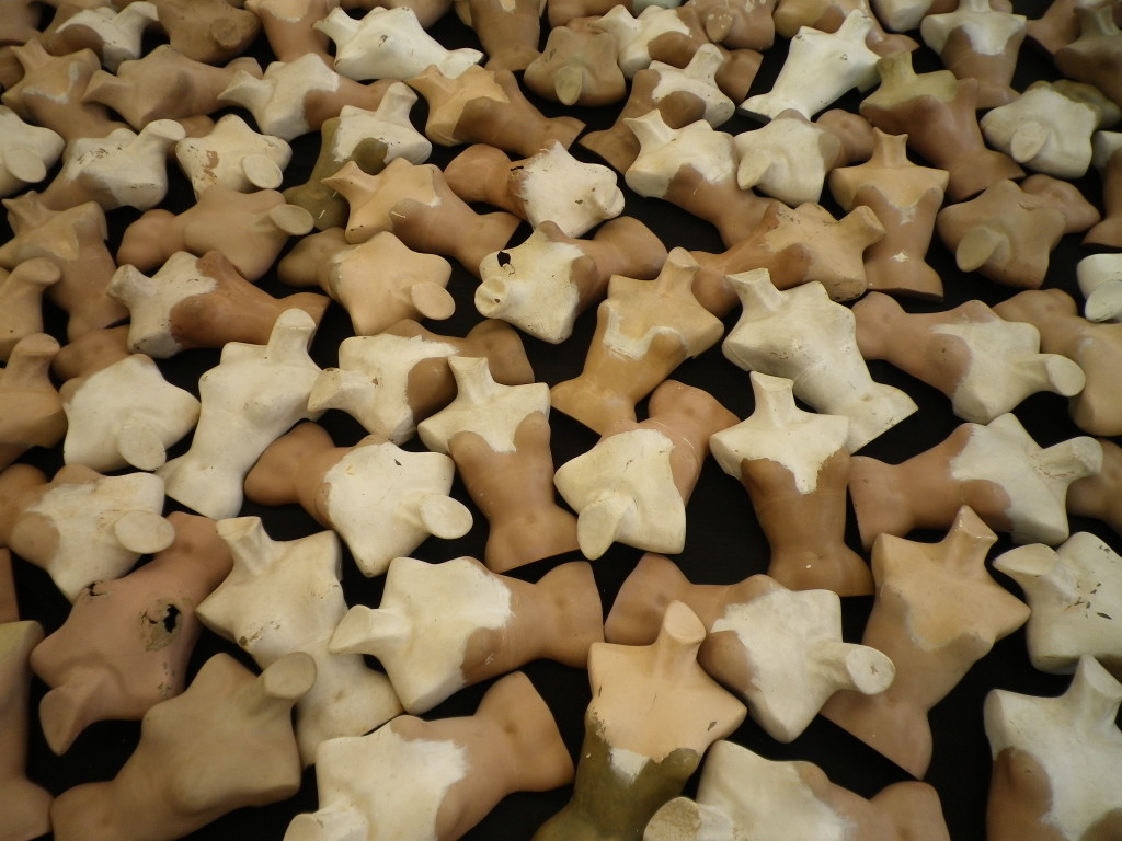 Overhead-billede af talrige små keramiske torso-figurer i creme- og sandfarver, tekstureret kunstnerisk arrangement